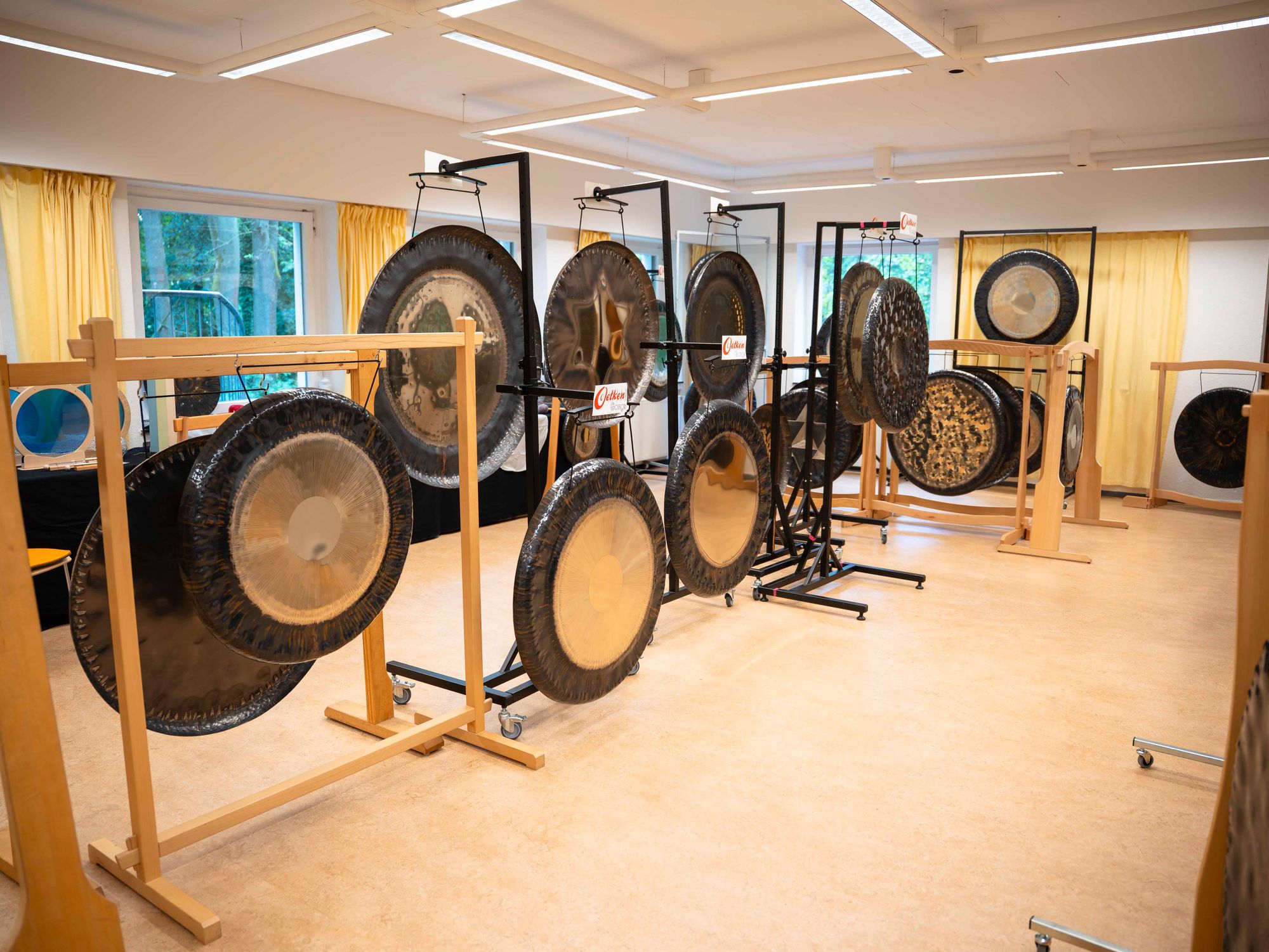 Mehrere große Gongs an Holzständern in einem hellen Raum, Symposium 2026
